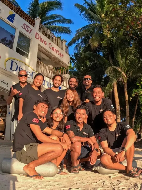 Groupe de personnes souriantes devant le centre de plongée ensoleillé