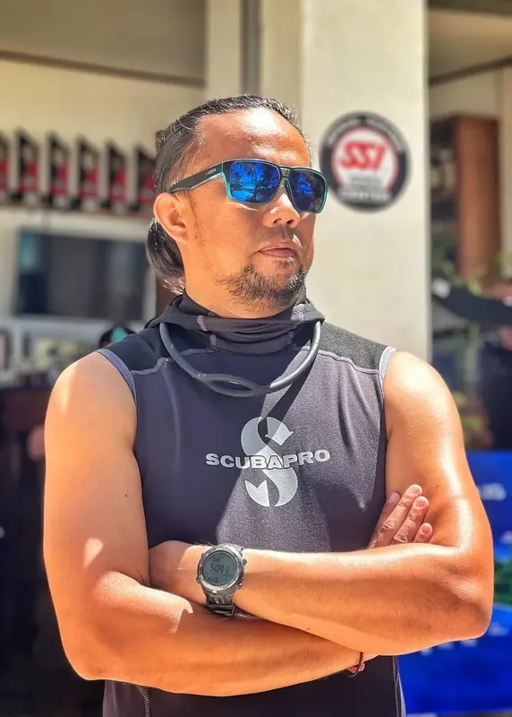 Homme portant des lunettes de soleil et un débardeur Scubapro les bras croisés