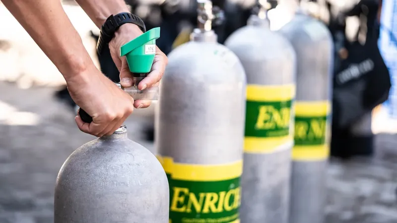 Main manipulant un manomètre sur une bouteille de plongée remplie