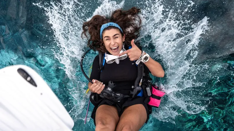 Plongeuse souriante avec signe OK, équipement complet, éclaboussures d'eau