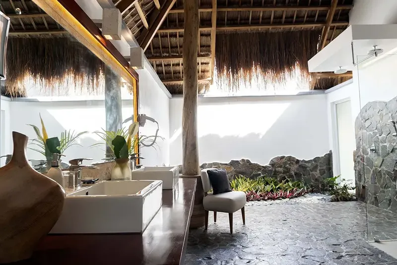 Salle de bain ouverte sur l'extérieur avec végétation luxuriante et douche