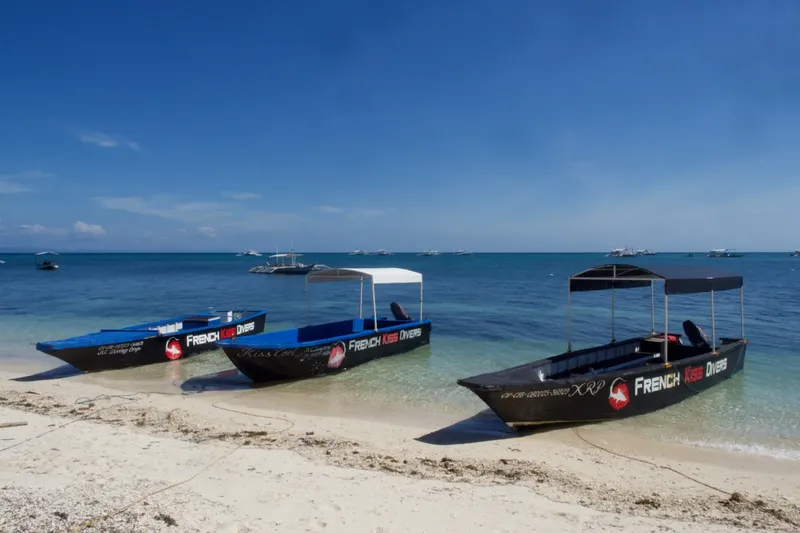 Trois bateaux de plongée échoués sur une plage de sable blanc