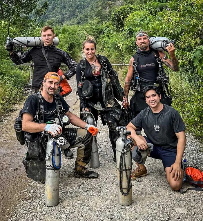 Groupe de plongeurs souriants équipés près d'une végétation luxuriante