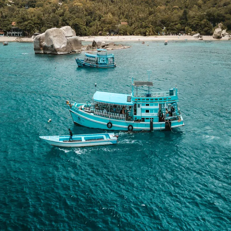 Plusieurs personnes à bord de bateaux turquoise en mer calme