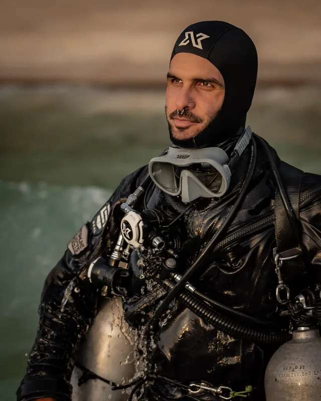 Plongeur en combinaison noire, masque et cagoule, regardant au loin