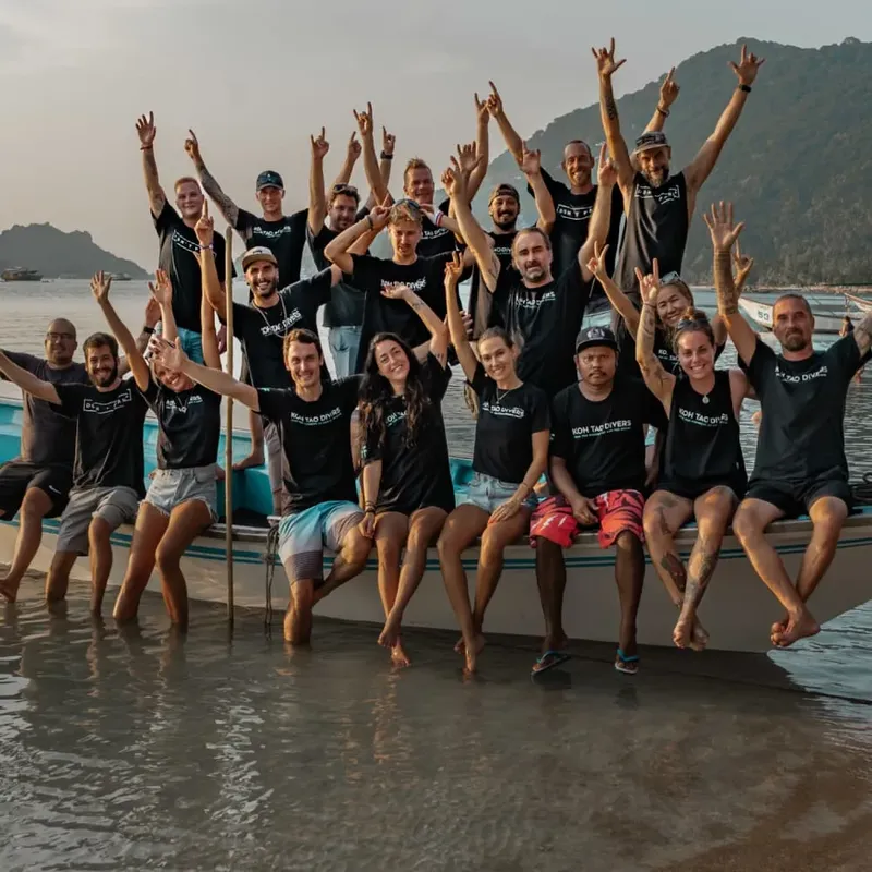 Groupe de personnes souriantes sur un bateau en mer, bras levés