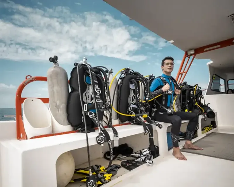 Plongeur assis sur un bateau avec son équipement complet prêt à plonger
