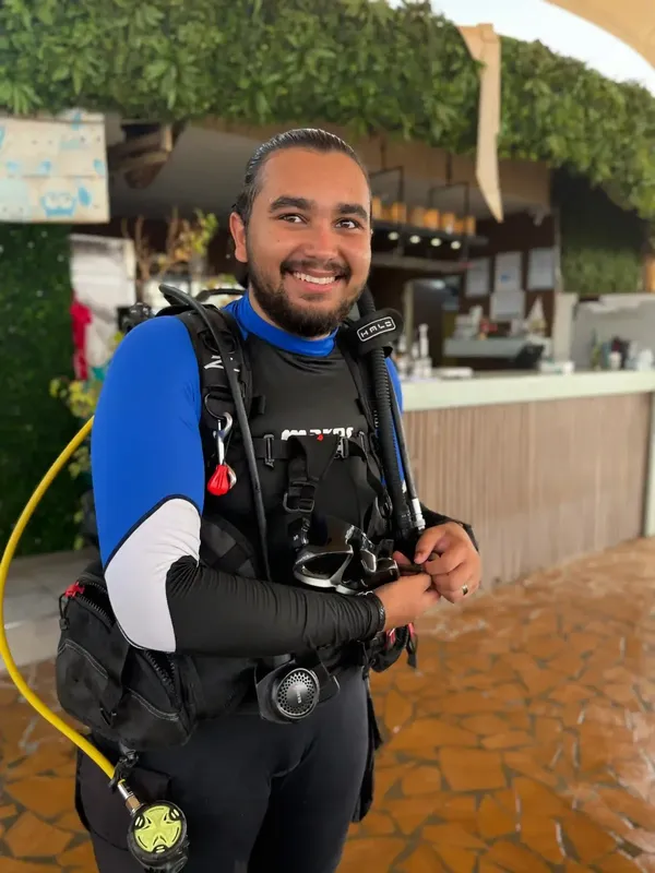 Plongeur souriant équipé de son matériel devant une végétation luxuriante