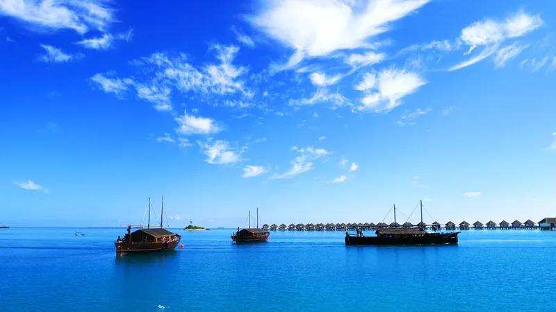 Trois bateaux traditionnels sur une eau turquoise sous un ciel bleu