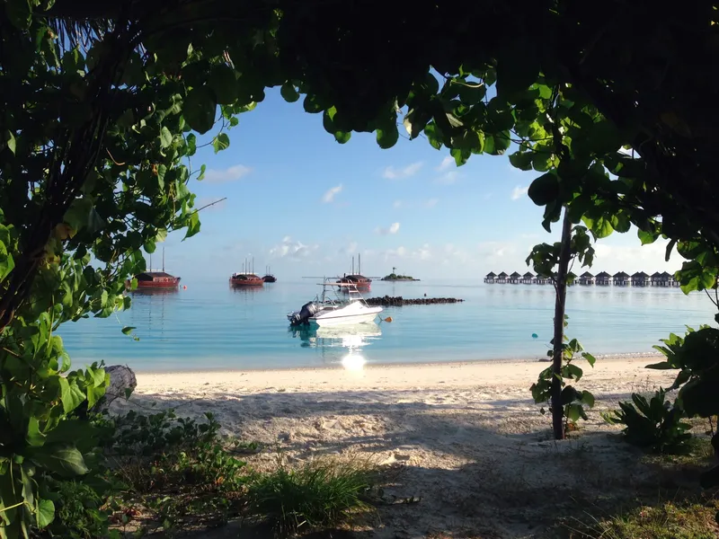 Plage tropicale avec bateaux amarrés dans une eau turquoise claire