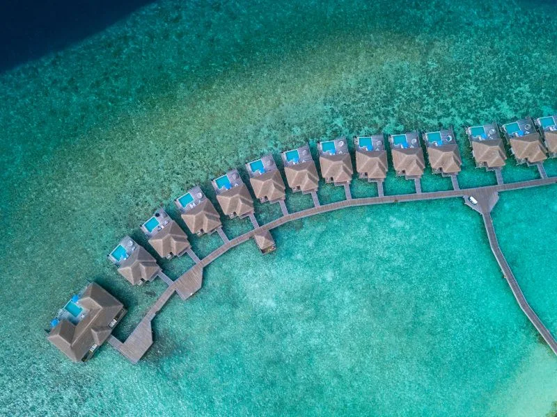 Vue aérienne d'une série de bungalows sur pilotis dans une eau turquoise