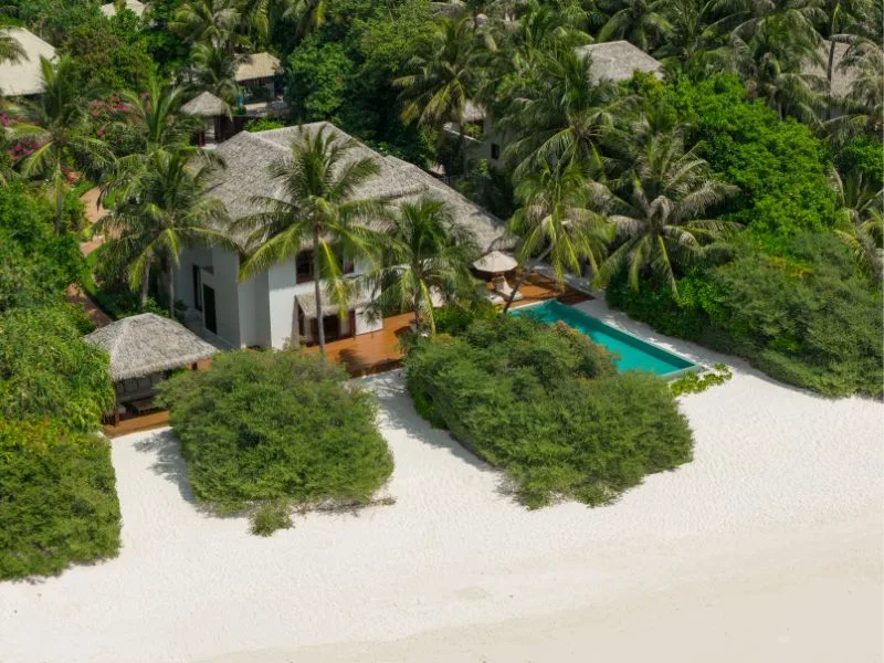 Vue aérienne d'une villa avec piscine, plage et végétation tropicale