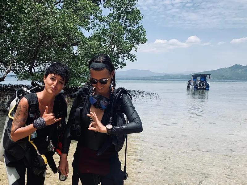 Deux plongeuses souriantes avec leur équipement sur une plage
