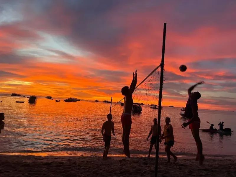 Joueurs de volleyball sur une plage au coucher du soleil