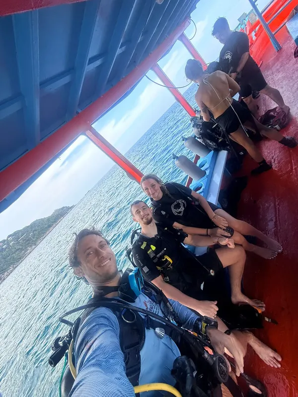 Plongeurs souriants sur un bateau, équipés pour une sortie en mer