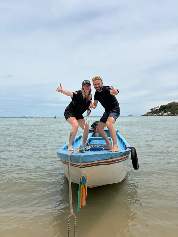 Deux personnes souriantes font un signe de pouce levé sur un bateau