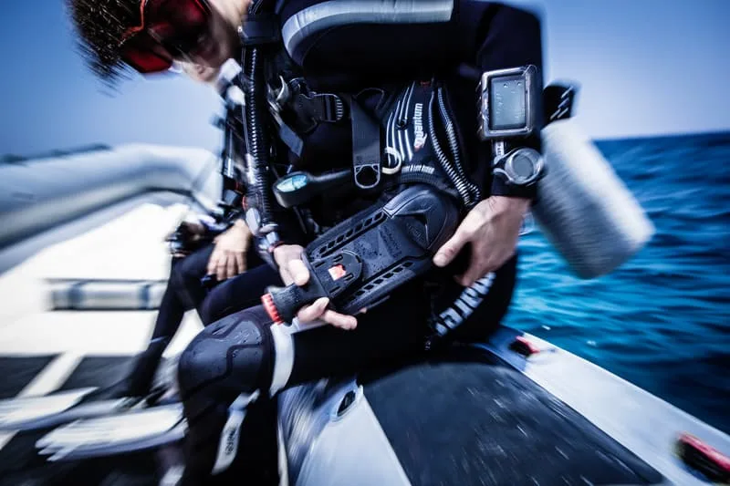 Plongeur préparant son équipement à bord d'un bateau pneumatique bleu