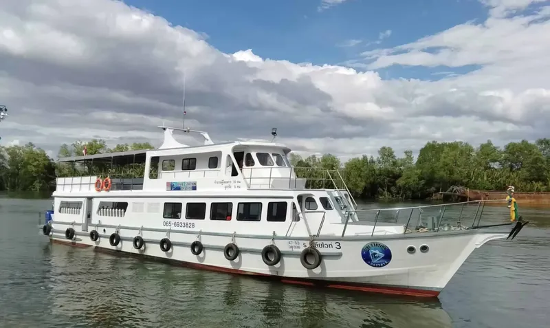 Grand bateau de plongée blanc amarré sur l'eau calme sous un ciel nuageux
