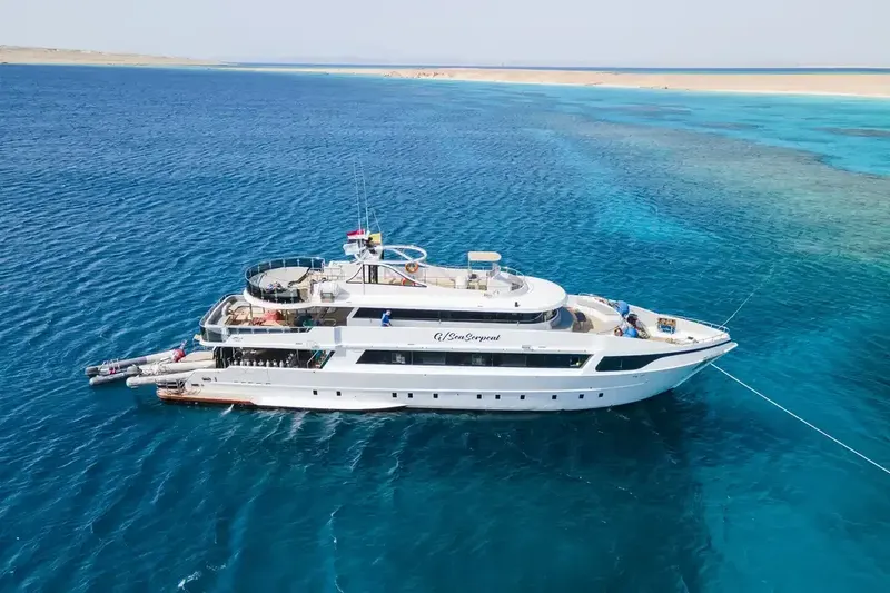 Grand bateau de plongée blanc navigue sur une mer turquoise claire