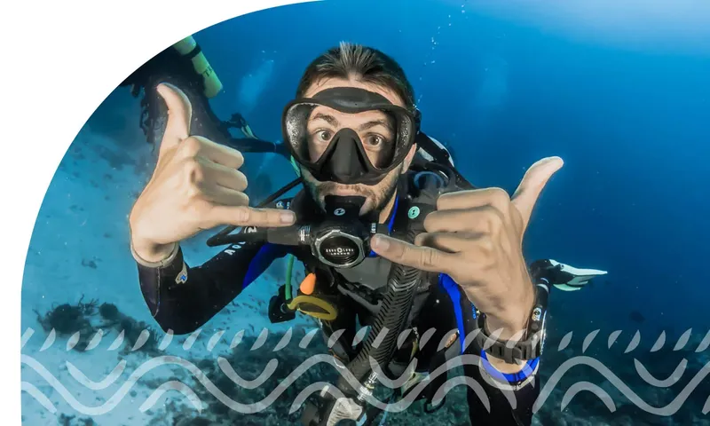 Plongeur souriant avec signe OK, équipé en pleine eau bleue