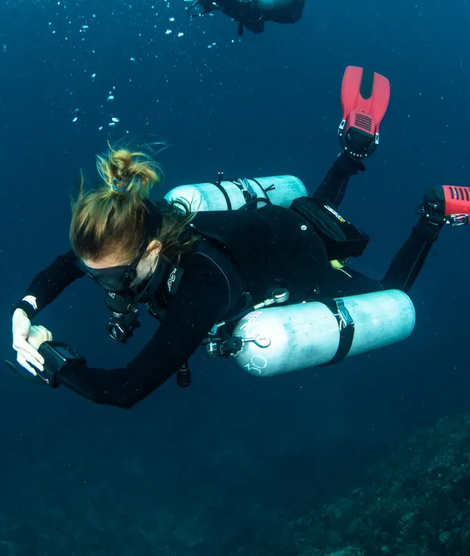 Plongeuse blonde manipule un appareil photo sous l'eau en bleu profond