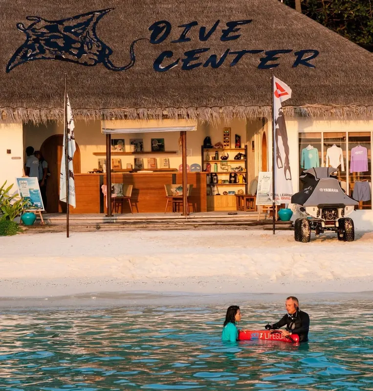 Plage tropicale avec centre de plongée et deux personnes dans l'eau