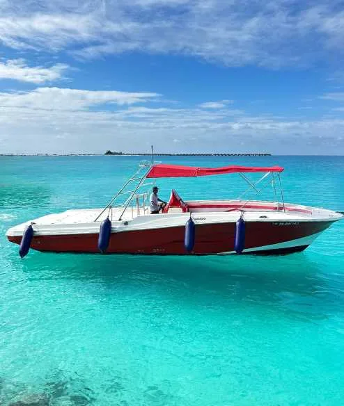Bateau de plaisance rouge et blanc naviguant sur une eau turquoise claire