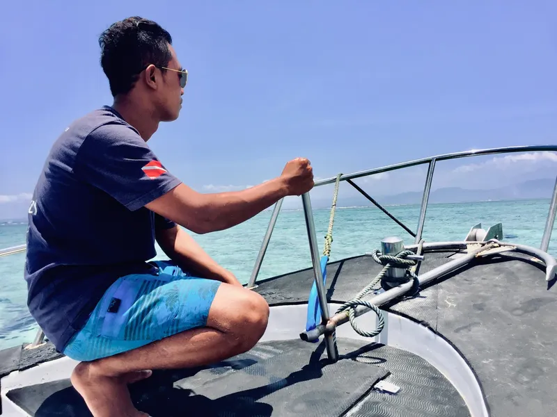 Homme sur un bateau de plongée, regardant vers l'horizon en mer