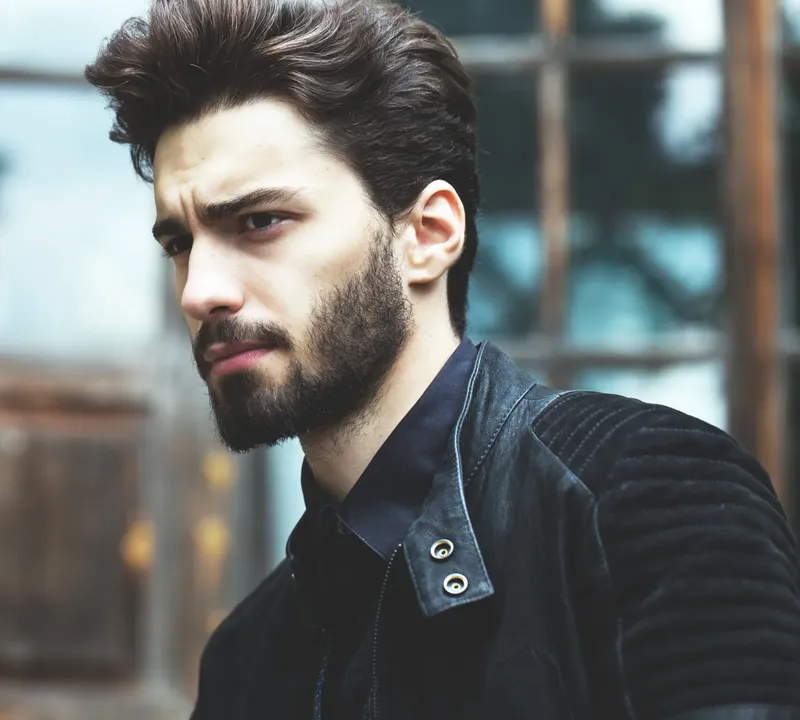 Portrait d'un jeune homme barbu regardant hors cadre avec une veste