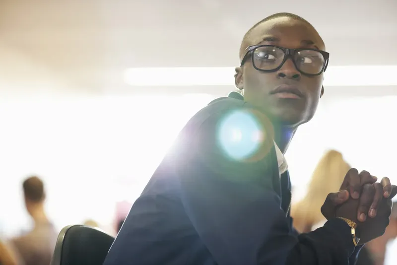 Jeune homme en salle de classe, regardant vers le haut, concentré