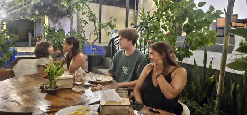 Quatre personnes assises autour d'une table en bois dans un jardin tropical