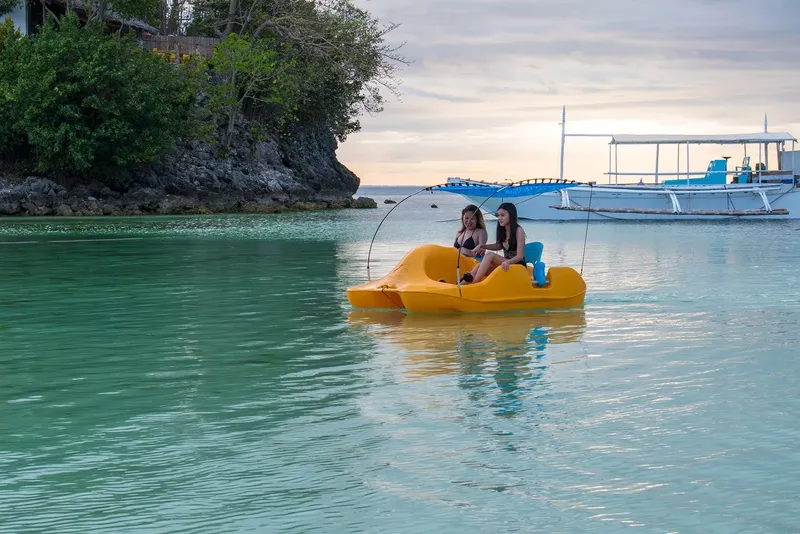 Deux femmes sur un pédalo jaune en mer turquoise calme