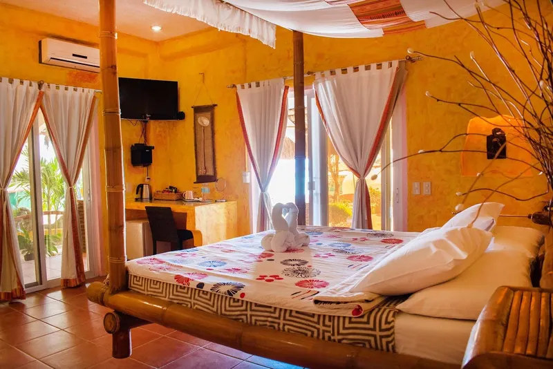 Chambre d'hôtel colorée avec lit à baldaquin et vue sur l'extérieur