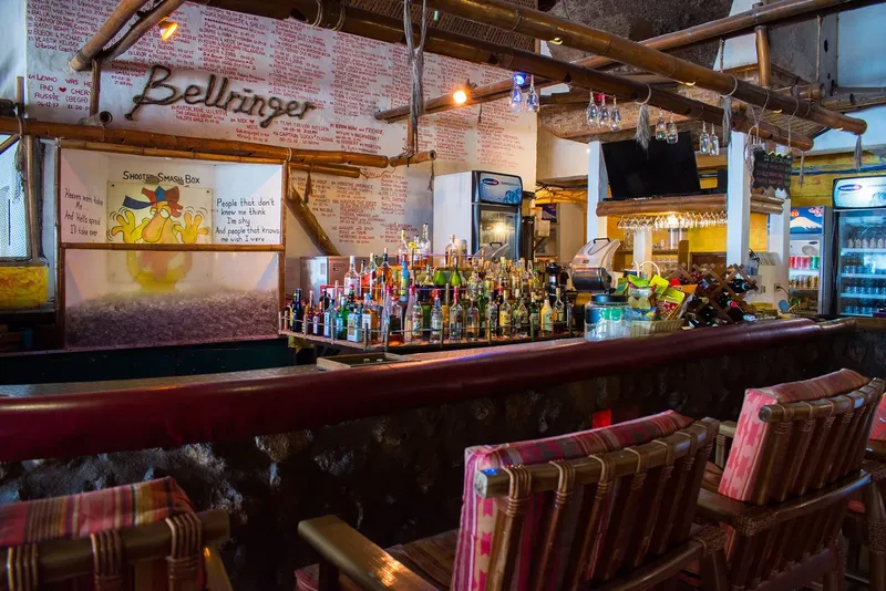 Bar coloré avec comptoir, bouteilles, chaises et murs décorés d'inscriptions