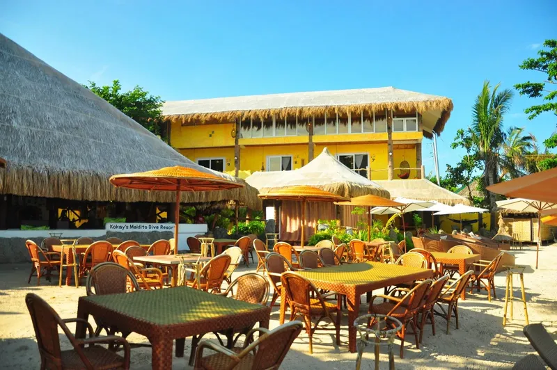 Terrasse de restaurant avec parasols et bâtiment jaune en arrière-plan