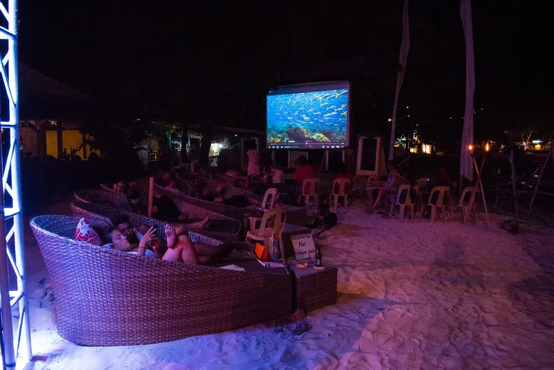 Public regardant un écran de projection sur une plage la nuit
