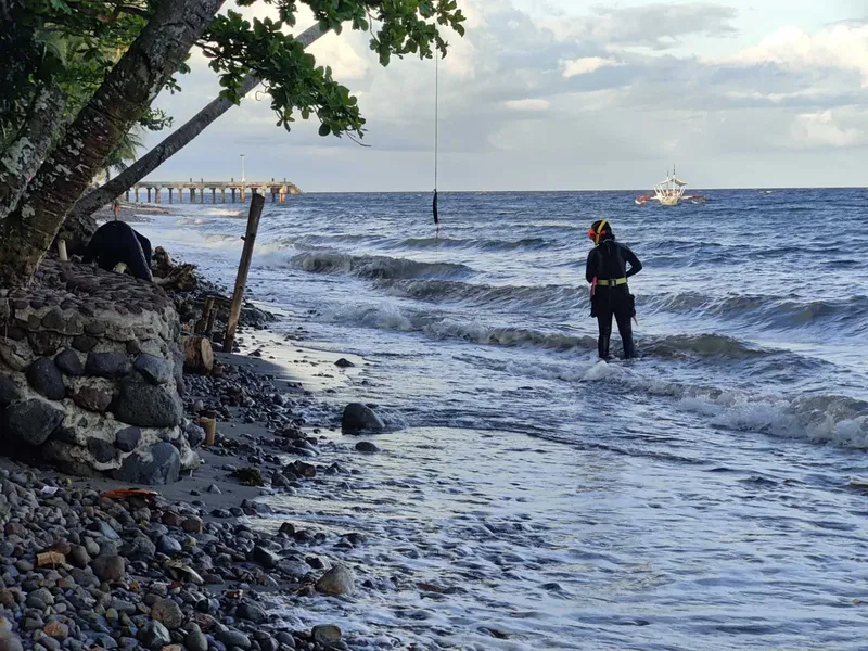 Plage rocheuse avec deux personnes et un bateau en mer