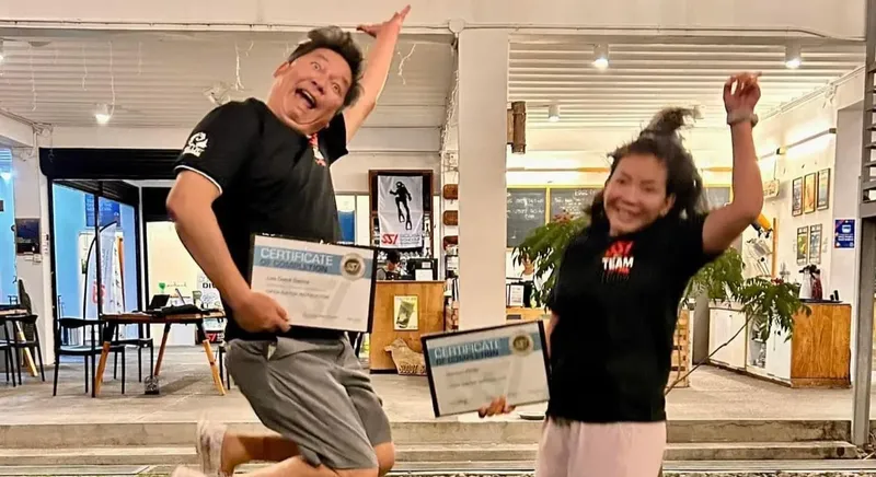 Deux personnes souriantes, tenant des certificats, devant un centre de plongée