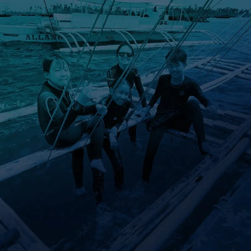 Quatre personnes souriantes en combinaison de plongée sur un bateau