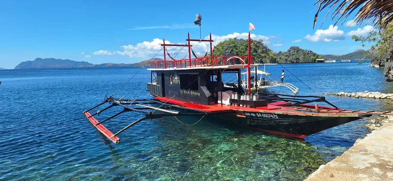 Bateau de plongée amarré dans une eau turquoise avec des personnes à bord