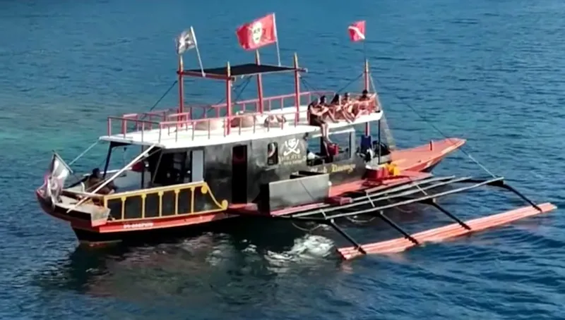 Bateau de plongée avec des passagers, drapeaux et vue sur la mer