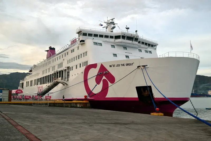 Grand ferry blanc et rose amarré à quai sous un ciel gris