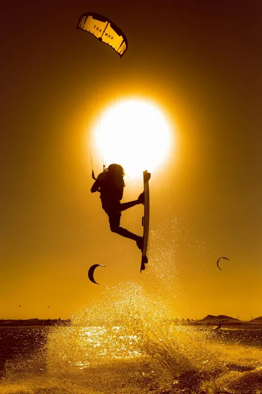 Kitesurfeur en plein saut au coucher du soleil sur l'eau