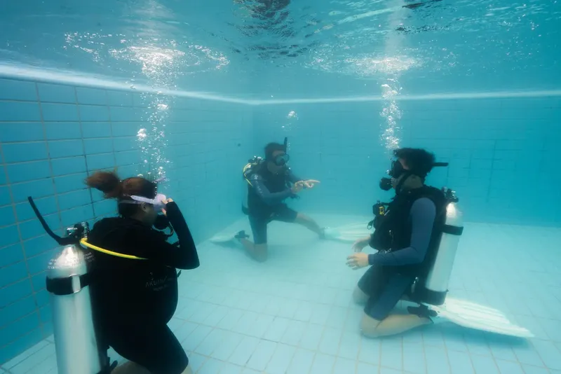 Trois plongeurs en formation dans une piscine, communication sous-marine