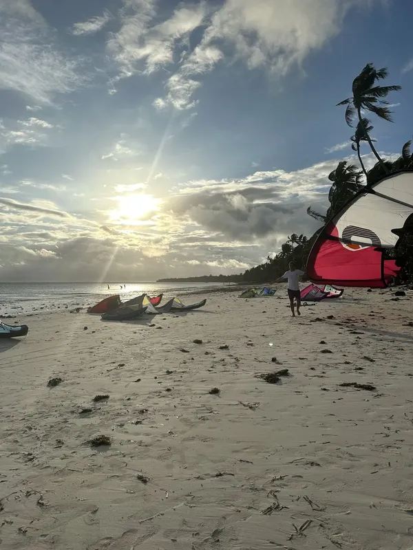 Plage avec des cerfs-volants, une personne et des kayaks au soleil
