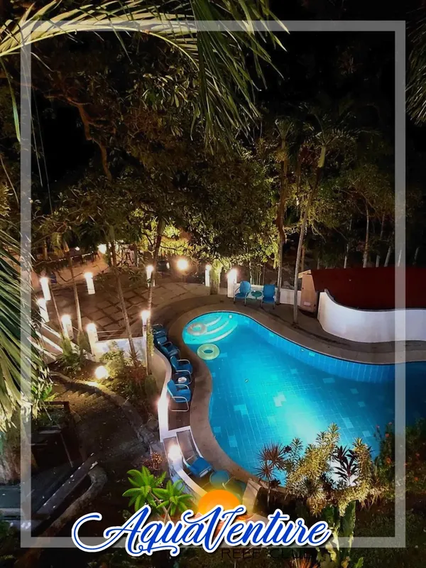 Piscine illuminée la nuit avec végétation luxuriante et logo AquaVenture