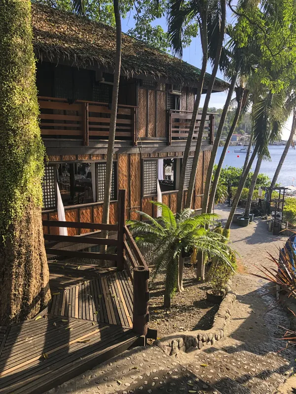 Bâtiment en bois et bambou avec végétation tropicale en bord de mer