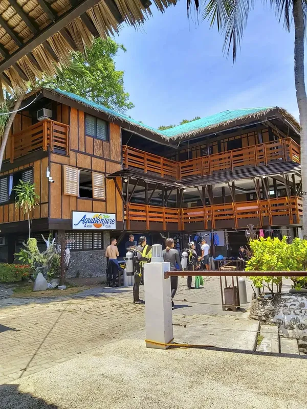 Bâtiment en bois avec des plongeurs et du matériel devant l'entrée