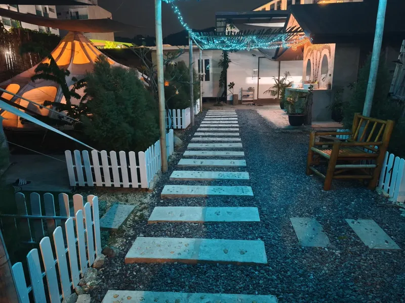 Allée pavée mène à des bâtiments éclairés avec des guirlandes lumineuses