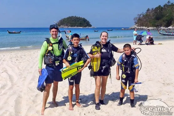 Groupe de plongeurs souriants sur une plage ensoleillée avec équipement